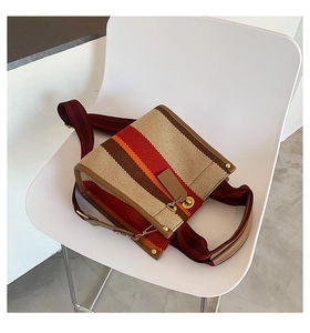 Detail of striped canvas tote with brown leather handles and woven shoulder strap