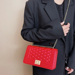 Sac à bandoulière en cuir matelassé rouge avec chaîne dorée porté par un mannequin