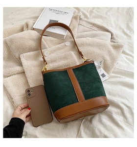 Detail of dark green suede and brown leather bucket bag with golden hardware and handle