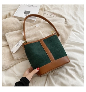 Detail of green suede and brown leather bucket bag with gold hardware and stitching