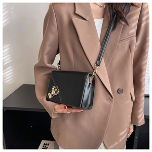 Detail of a chic black leather crossbody bag featuring a golden clasp and chain accent