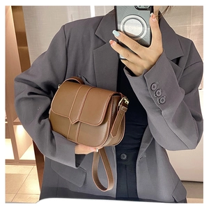 Braune Satteltasche aus Leder an einem Model mit grauem Blazer für den Alltag