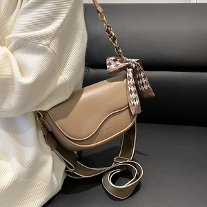 Khaki saddle bag with bow ribbon decoration and striped strap shown on model