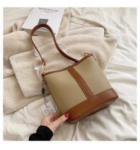 Detail of vintage color-block bucket bag in beige litchi leather and brown trim on textured fabric
