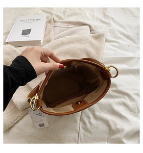 Detail view of brown leather bucket bag interior with magnetic closure and gold hardware