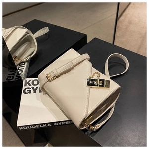 Detail of minimalist beige crossbody bag featuring textured leather and gold metal buckle