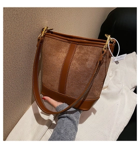 Detail of dark brown bucket bag with suede patchwork and white contrast stitching