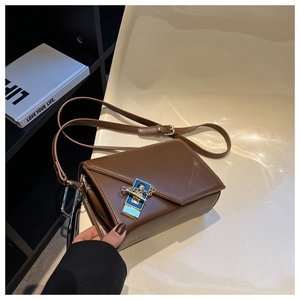 Detail of dark brown leather crossbody bag featuring a unique blue and gold metal clasp