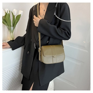 Olivgrüne Vintage-Satteltasche getragen zum schwarzen Blazer für minimalistischen Stil
