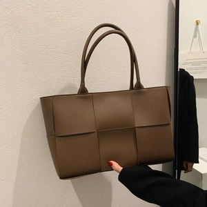 Deep brown large woven tote bag with wide leather straps in a minimalist fashion style