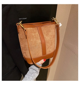 Detail of a brown bucket bag with contrast texture stitching and gold hardware buckle