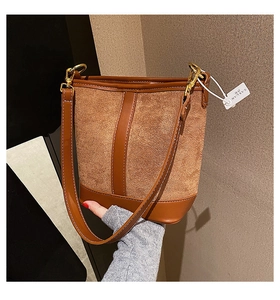 Detail showing brown suede stitching and white contrast seams on the bucket bag