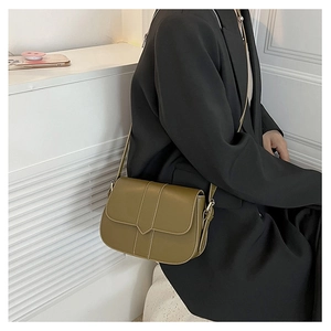 Olivgrüne Umhängetasche aus Leder auf schwarzem Blazer für einen minimalistischen Stil