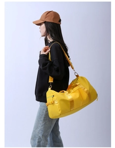 Yellow duffel bag with adjustable strap shown side-carried for travel and gym use