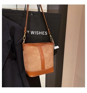 Detail of brown patchwork bucket bag featuring suede texture and smooth leather straps