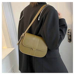 Olivgrüne Satteltasche mit Vintage-Lederriemendetail getragen über schwarzem Blazer