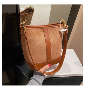 Detail of the brown patchwork bucket bag featuring suede texture and gold metal rings