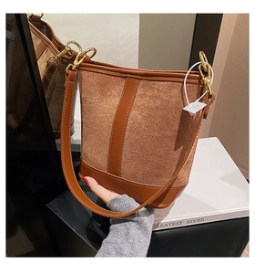 Detail of brown suede bucket bag with leather patchwork and golden hardware on display