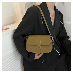 Olivgrüne Satteltasche als Umhängetasche über einem schwarzen Blazer für Retro-Look