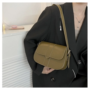 Olivgrüne Satteltasche mit goldener Schnalle, getragen zu einem schwarzen Blazer