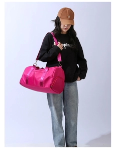Hot pink large capacity travel bag worn crossbody by a model for gym and weekend trips