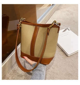 Detail of lychee pattern leather bucket bag with gold hardware and white contrast stitching