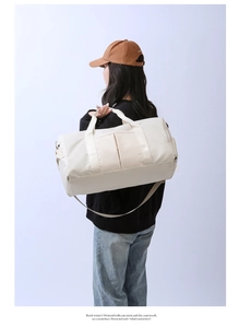 Detail of a beige large capacity travel bag worn by a model in a studio setting