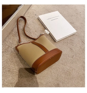 Detail view of a vintage beige and dark brown leather bucket bag with contrast stitching