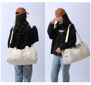 Side view of beige travel duffel bag with detachable shoulder strap and multi-pocket design