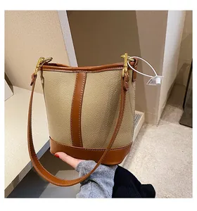 Detail of a beige lychee pattern bucket bag with brown leather contrast and gold hardware