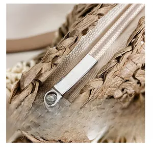 Detailed macro view of the smooth silver metal zipper on a woven straw tote bag