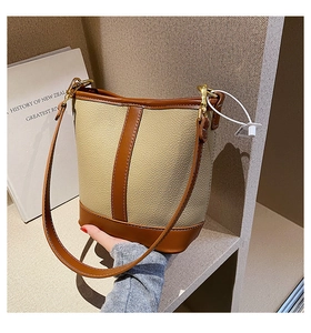 Detail of a minimalist two-tone leather bucket bag with gold hardware and contrast stitching