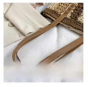 Detail showing the brown faux leather strap and wave-pattern woven texture of the tote bag