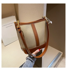 Detail of vintage beige bucket bag with dark brown leather stitching and gold buckle