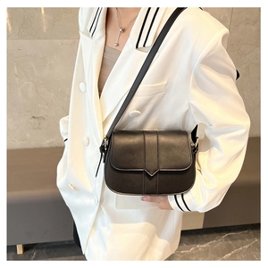 Detail einer schwarzen matten Satteltasche aus Kunstleder an einem Model im weißen Anzug