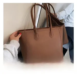 Close-up of brown leather tote bag featuring slim shoulder straps and vertical stitching