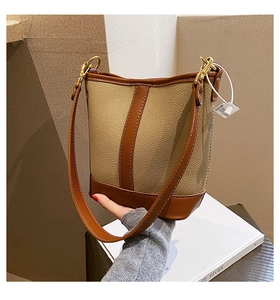 Detail of a brown and khaki patchwork bucket bag with golden hardware hooks