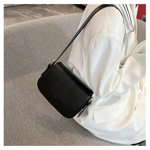 Detail der minimalistischen schwarzen Satteltasche mit goldener Metallschnalle und Leder
