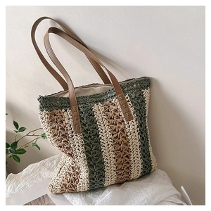 Detail of striped woven tote bag featuring brown leather straps and reinforced stitching