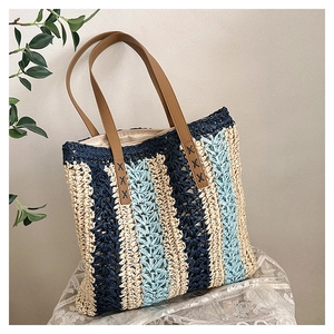 Detailed close-up of woven straw tote bag texture and reinforced leather handle stitching