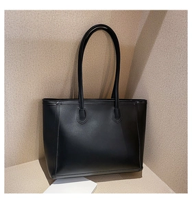 Detailed close-up of a minimalist black leather tote bag with long shoulder straps
