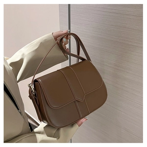 Nahaufnahme einer vintage dunkelbraunen Satteltasche mit Klappverschluss und goldenen Details