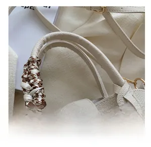 Detail of off-white lychee texture tote bag handle wrapped in houndstooth silk scarf