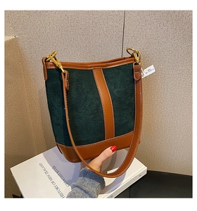 Detail of vintage green suede bucket bag with brown leather straps and gold metal hooks
