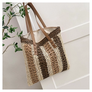 Close-up of woven straw tote bag with brown leather handles and striped texture