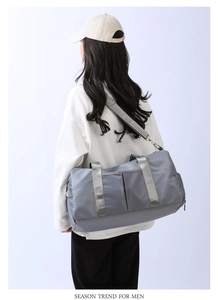 Model wearing a grey large capacity travel duffel bag with waterproof nylon fabric details
