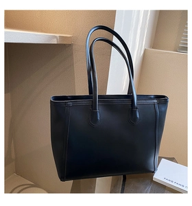 Minimalist black leather tote bag with fine stitching shown in a stylish studio setting