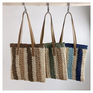 Close-up of three woven tote bags in striped colors with long brown leather handles