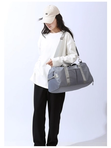 Gray large capacity travel bag shown as a crossbody gym bag worn by a model in casual wear