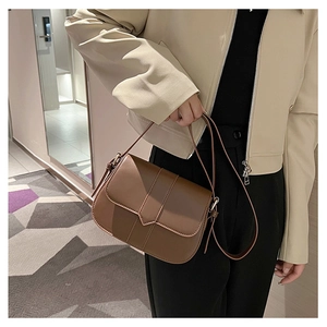 Detailansicht einer braunen Vintage-Satteltasche mit Ziernähten und goldenen Beschlägen